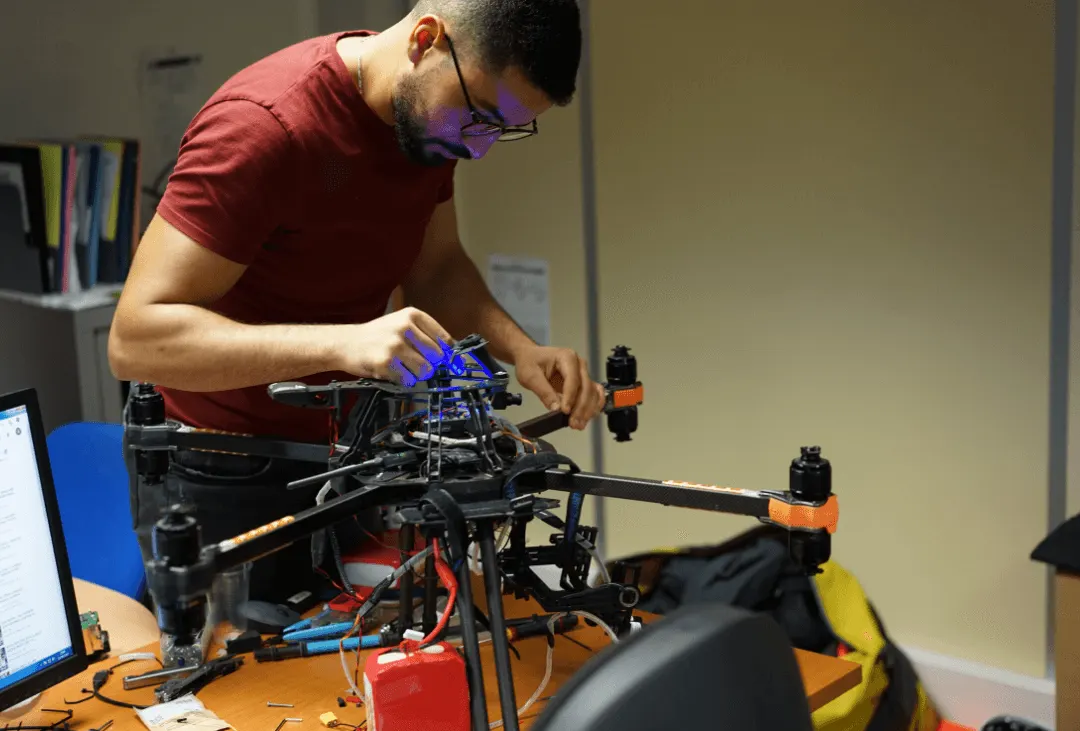 Amine monte l’électronique d’un drone octocoptère sur un établi